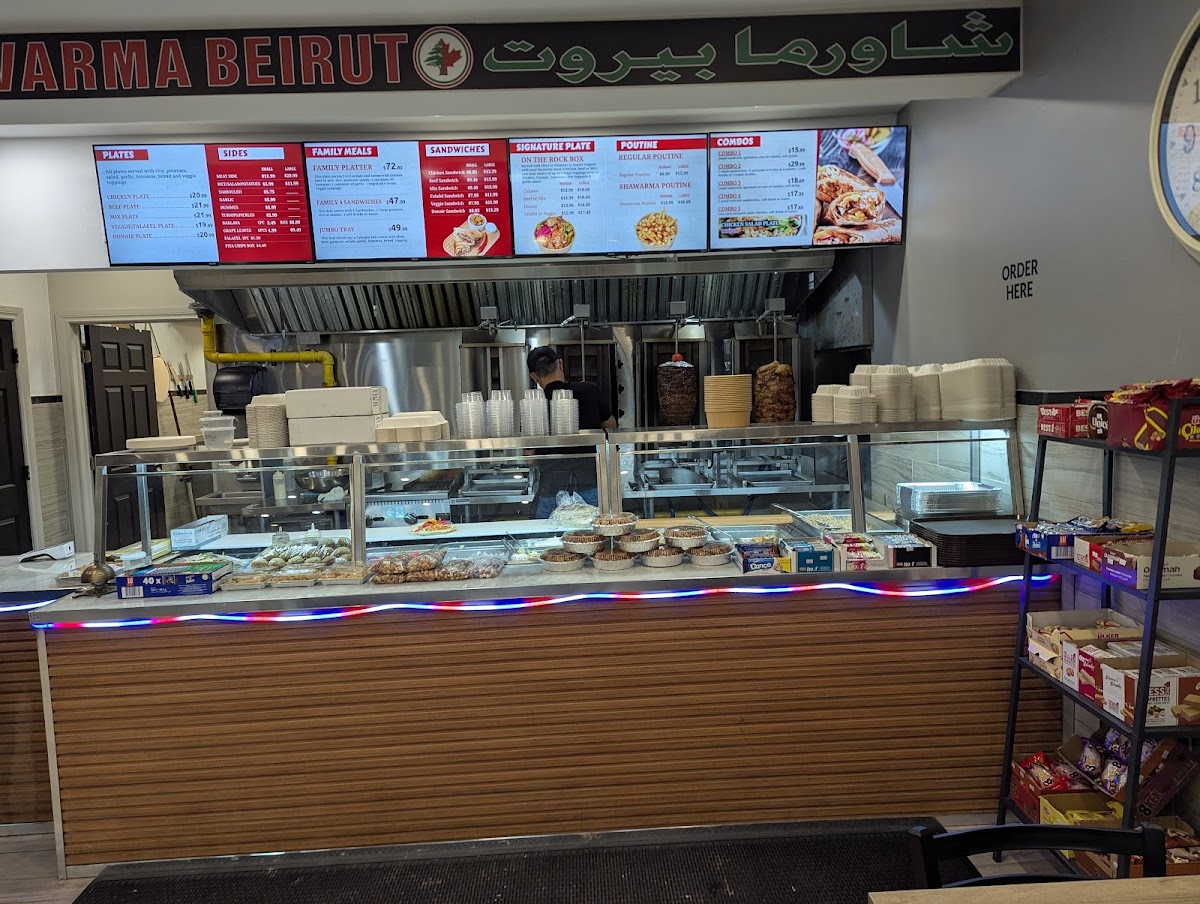 The Shawarma Beirut ordering counter with lit menu boards, display case and Arabic signage